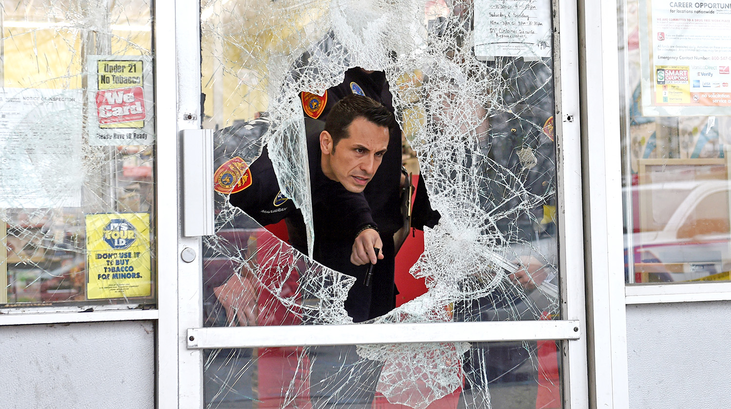 an officer examining a broken glass door